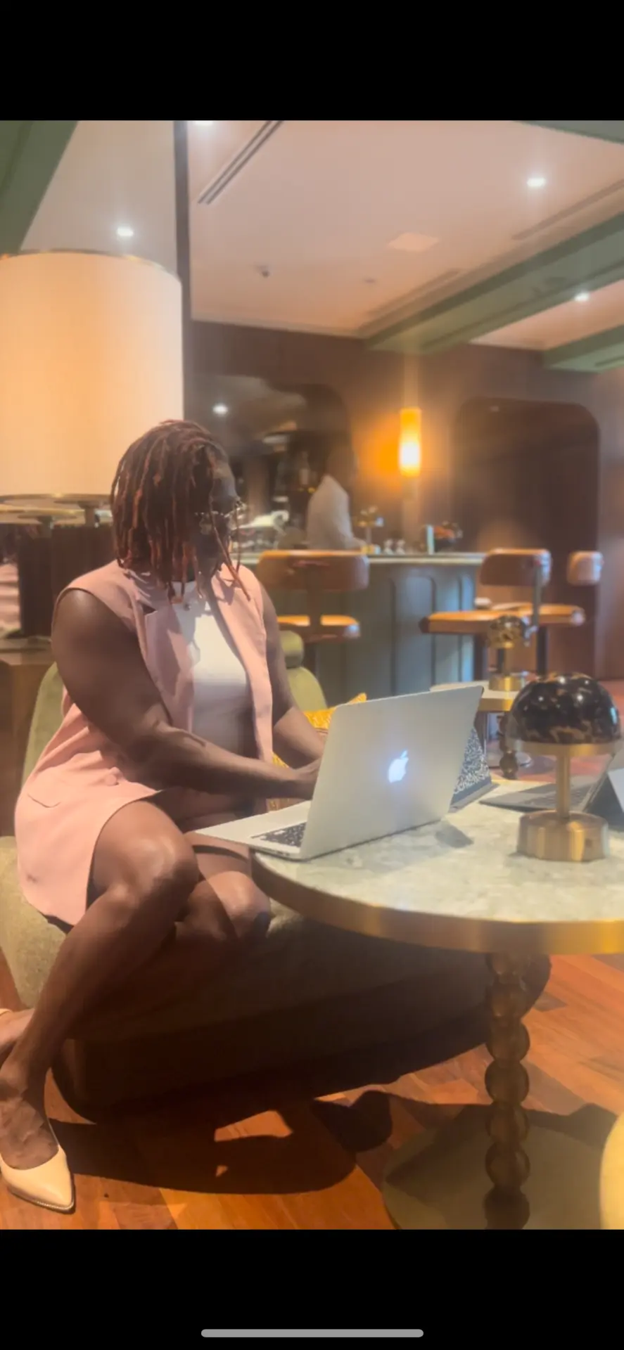 Antwonette working on a laptop in a warmly lit hotel lounge