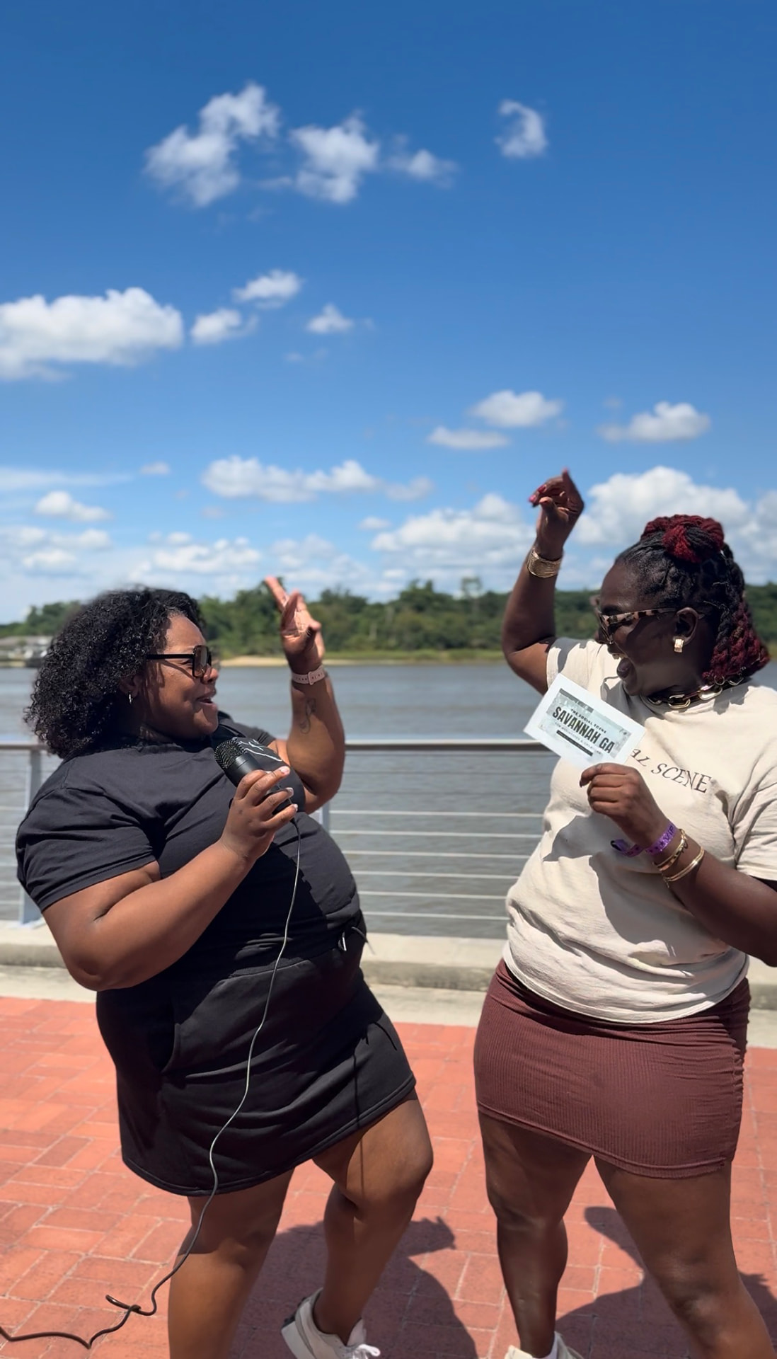Antwonette interviewing someone with a handheld microphone on the Savannah riverfront