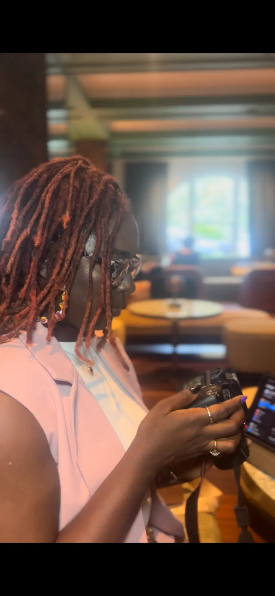 Antwonette holding a camera, observing a hotel lounge