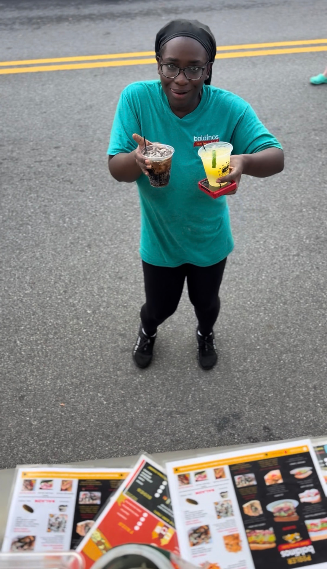 A restaurant team member bringing out two drinks curbside