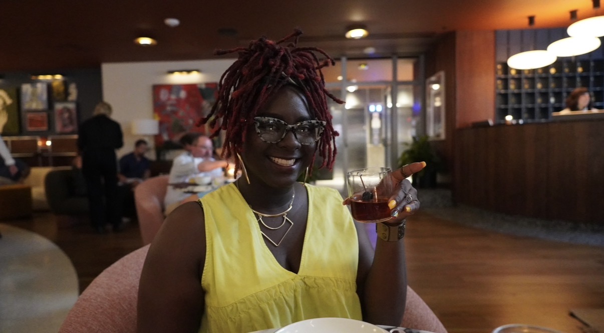 Antwonette seated in a restaurant dining room holding a cocktail
